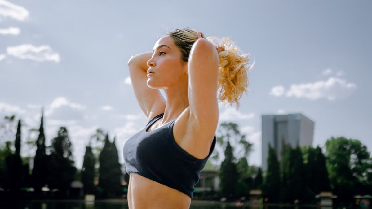 Fit woman in a black tank top enjoys a sunny workout outdoors in Ciudad de México, embracing wellness and healthy living.